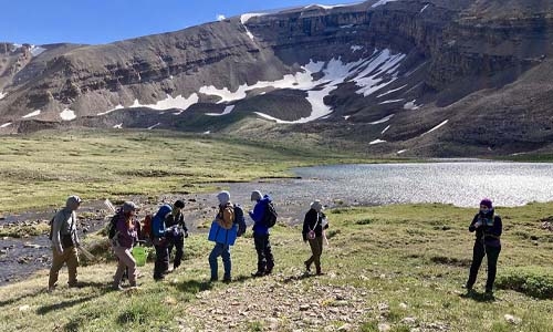 Group of researchers near a body of water with mountains in background